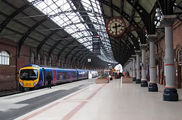Druk centraal treinstation met moderne trein en historisch klokwerk, waar nieuwe vloerbedekking ’s nachts werd gedroogd om 8 miljoen reizigers per jaar zonder hinder te laten doorstromen.